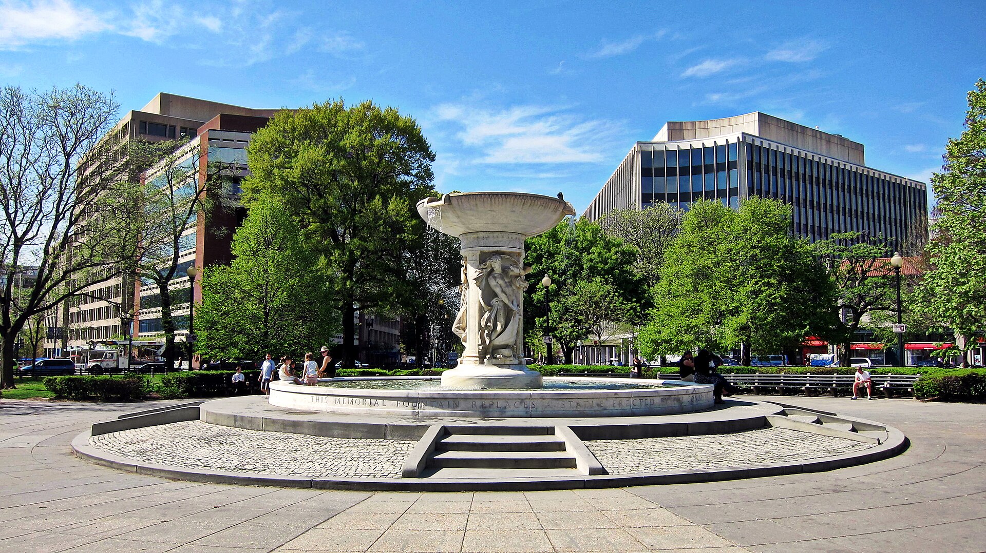 The white marble fountain in the center of Dupont Circle, Washington DC, surrounded by trees and benches