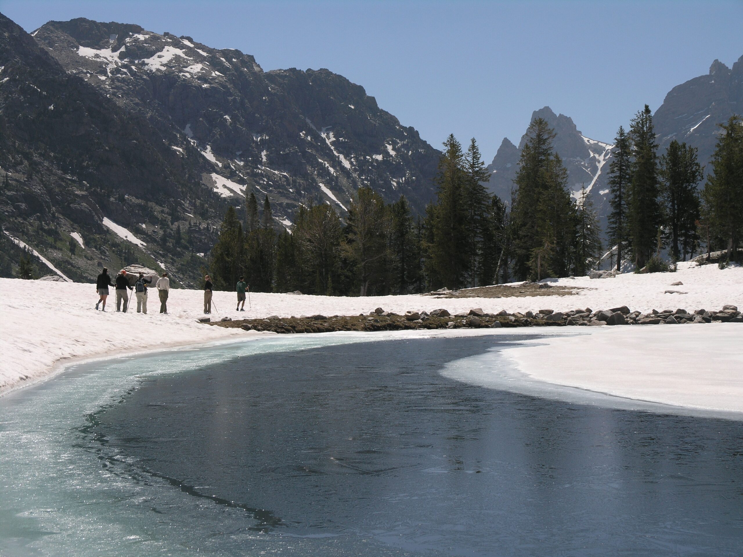 Lake Solitude still partly frozen with snow on the ground in early July, showing late snowmelt in Grand Teton National Park