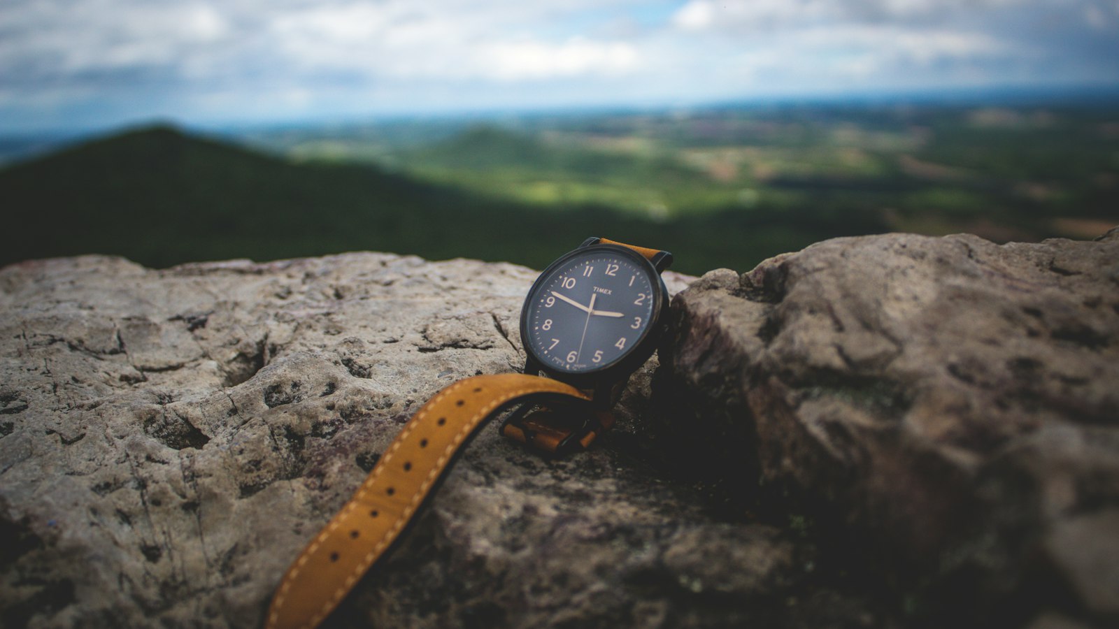 Black analog field watch on a stone