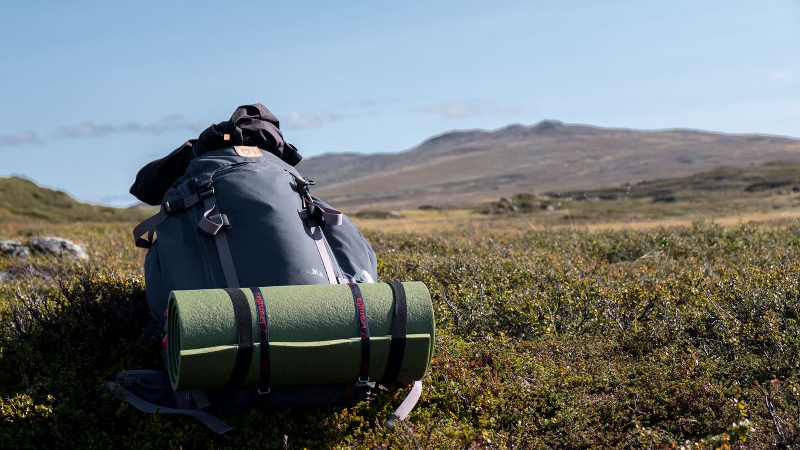 Backpack with a sleeping mat on a grassy field in the Swedish mountains