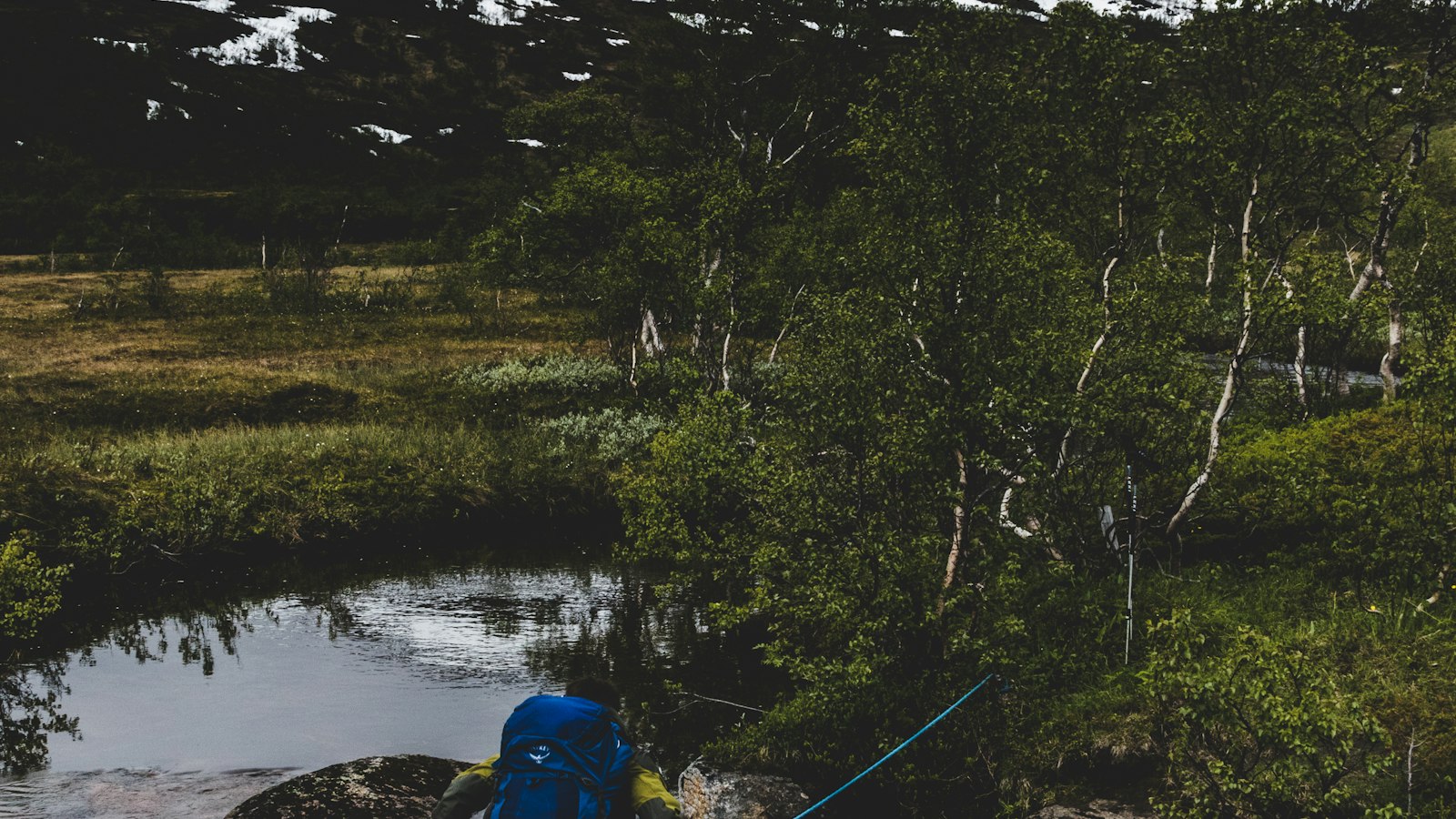 Backpacker crossing a mountain stream in Norway on a weekend trip