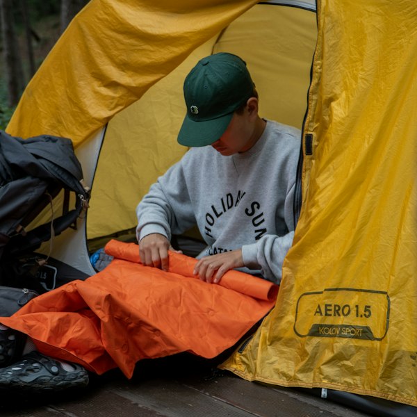 Backpacker inside a tent next to a sleeping bag and wide sleeping pad
