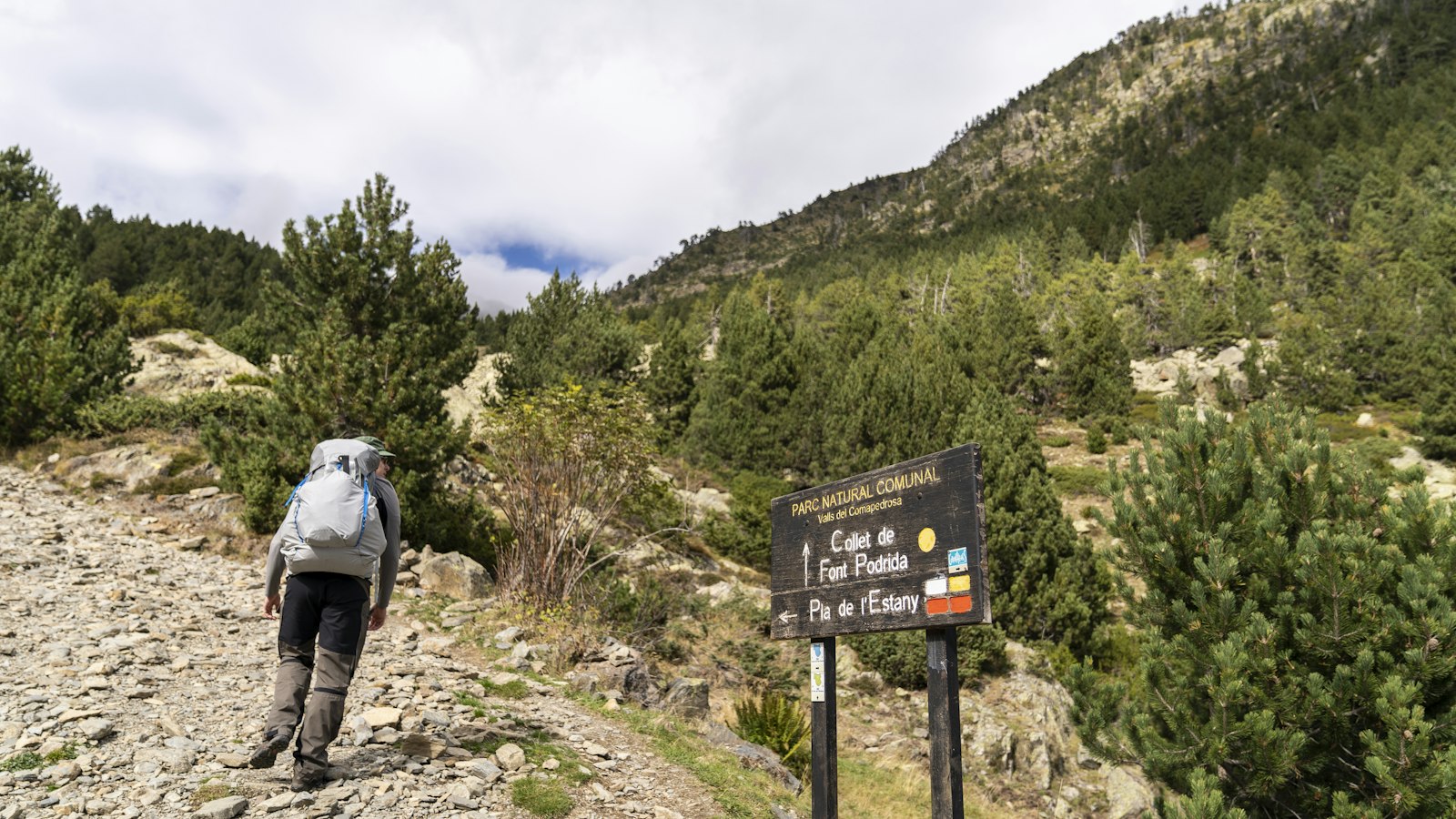 Backpacker walking uphill on a gravel trail in the Pyrenees