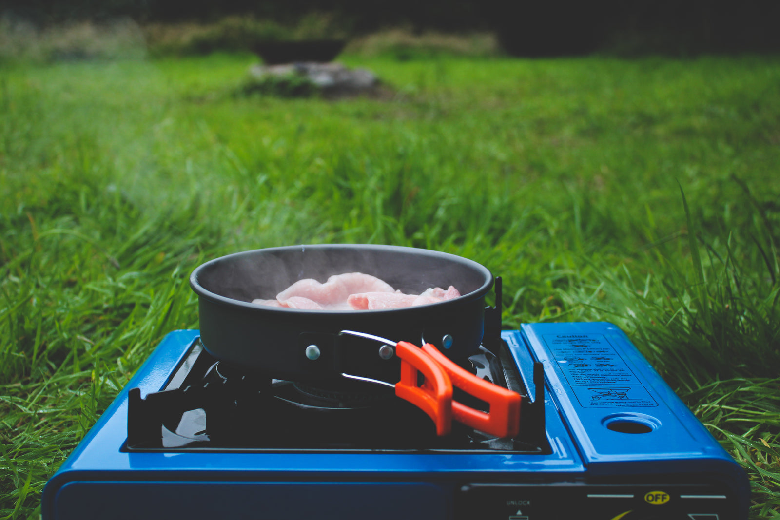 Food sizzling in a cast-iron pan over a campfire at a campsite