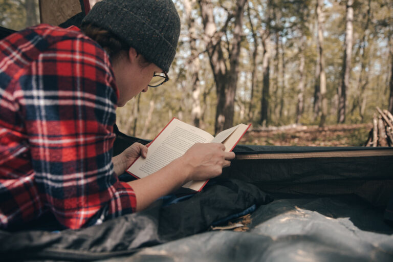 Woman reading a hiking book inside a camping tent