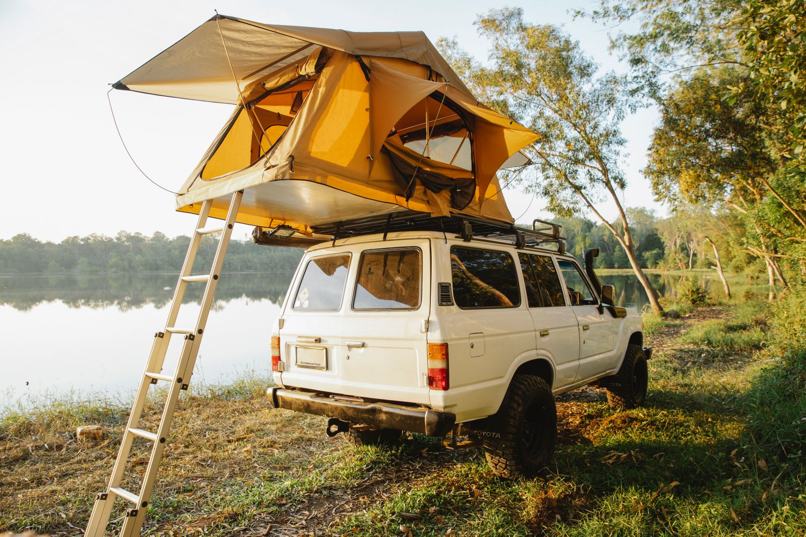 SUV with rooftop tent at a lakeside campsite, the kind of car camping trip where a rechargeable camping shower is useful