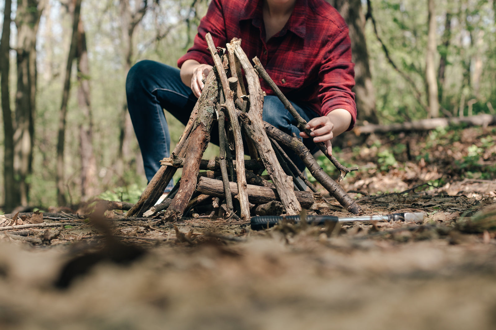 Camper building a campfire in the forest, a core wilderness survival skill