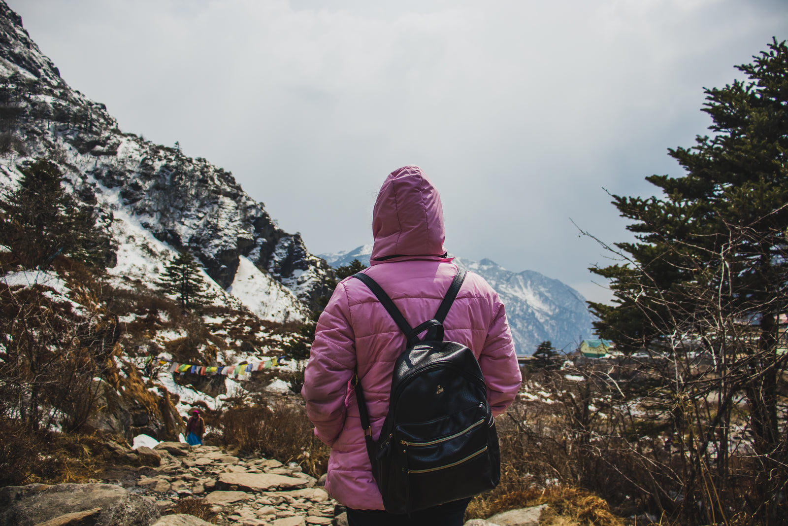 Hiker in a bright waterproof jacket walking a mountain trail