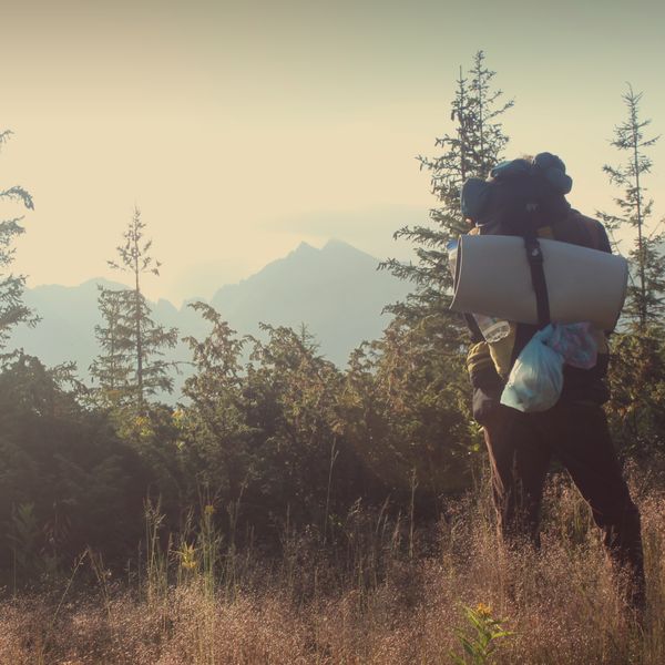 Hiker carrying a backpack with a foam sleeping mat in the mountains
