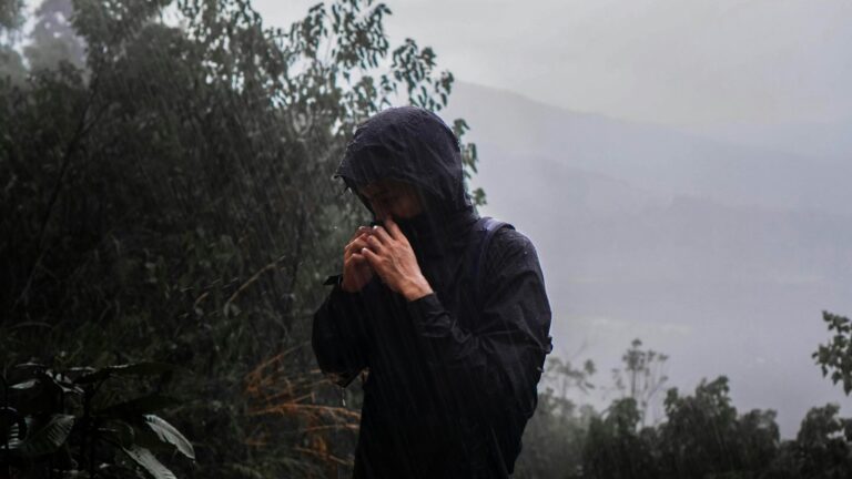 Hiker in rain gear standing in the rain on a trail