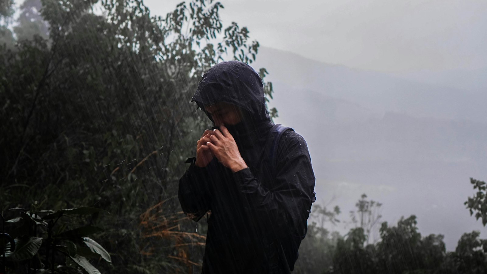 Hiker in rain gear standing in the rain on a trail