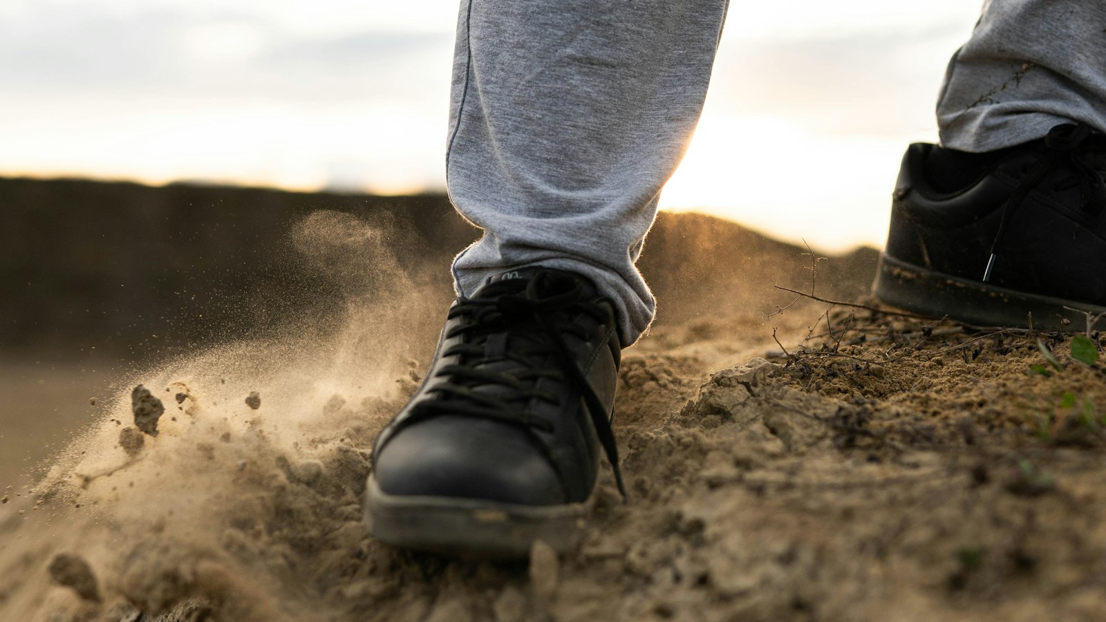 Hiker's shoes kicking up dust on a dry dirt trail