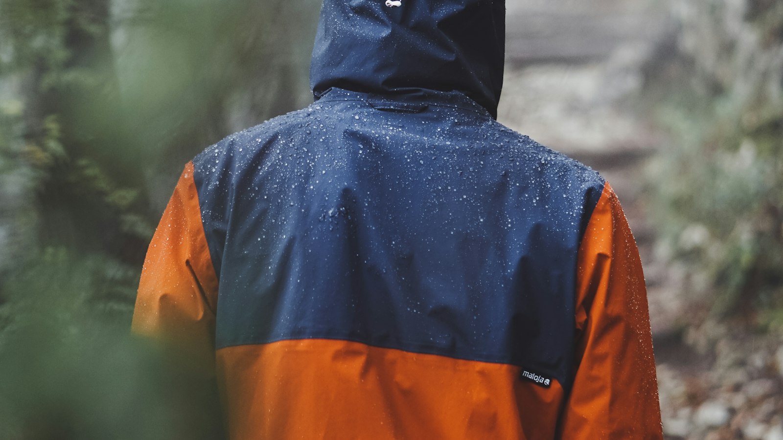 Hiker wearing an orange and blue raincoat on a rainy day outdoors