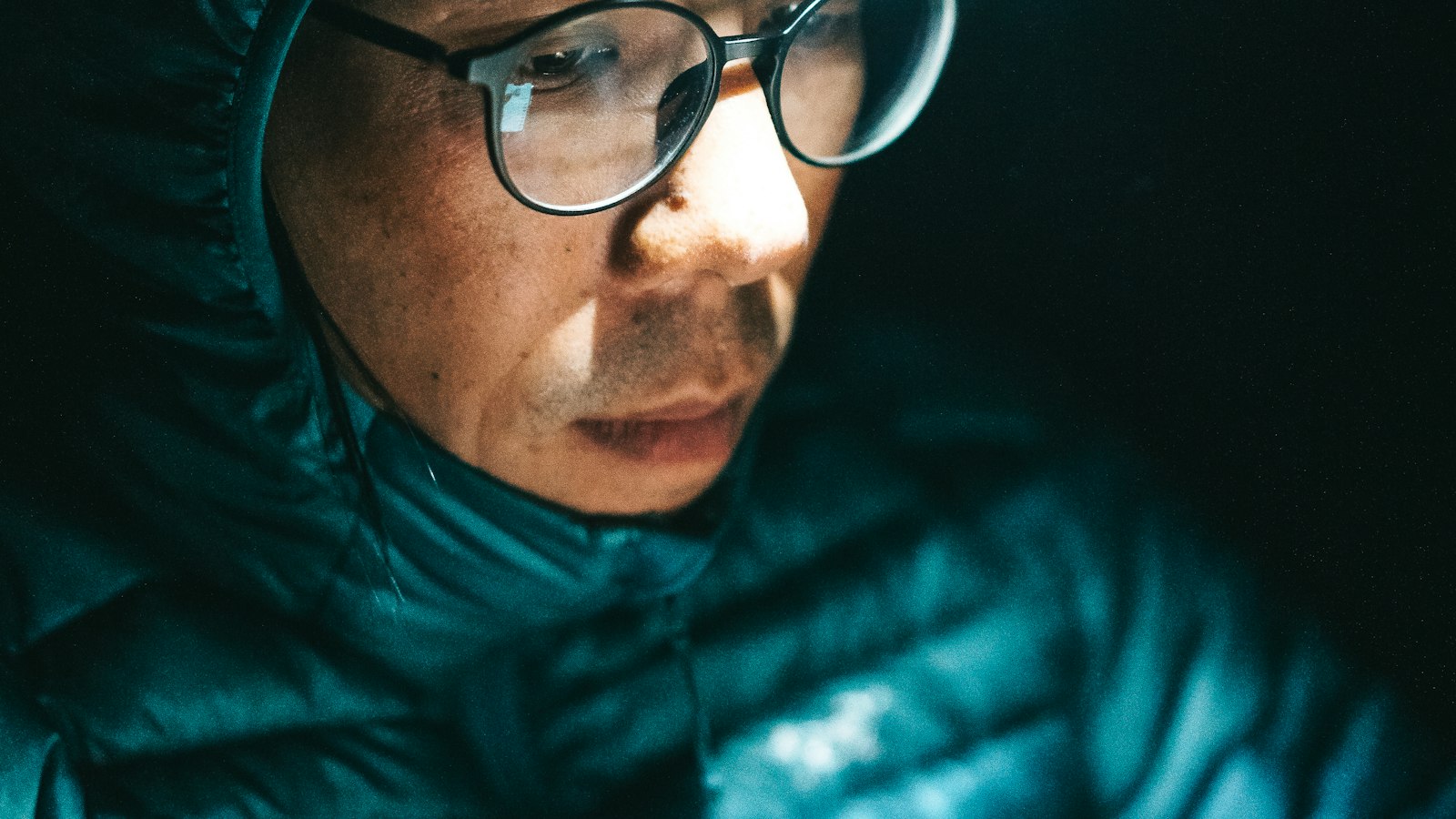 Hiker in a blue jacket wearing a headlamp outdoors