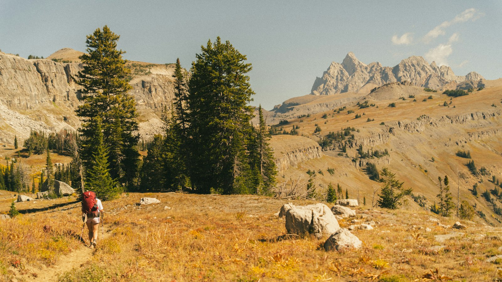 Hiker with a backpack walking on a mountain trail