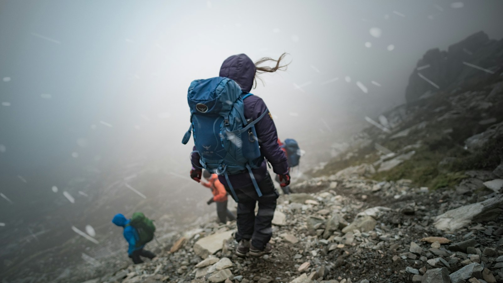Hiker with a backpack walking up a rocky hill