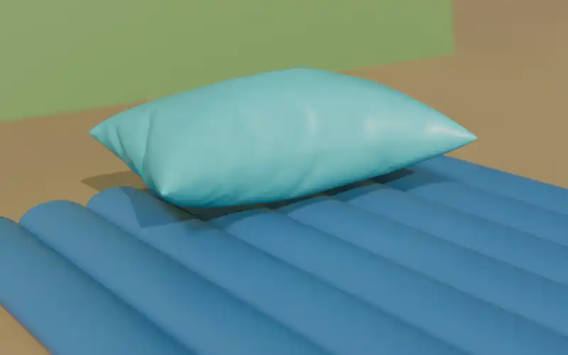 Inflatable camping pillow resting on an insulated sleeping pad