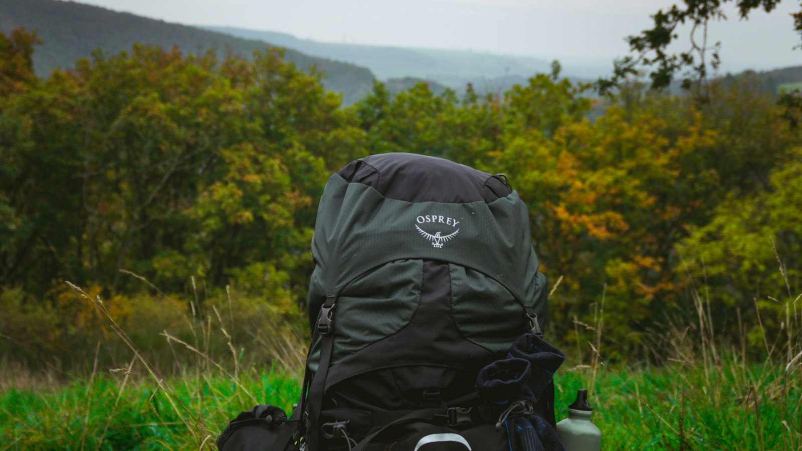 Lightweight 48 liter hiking backpack resting on grass with hills behind