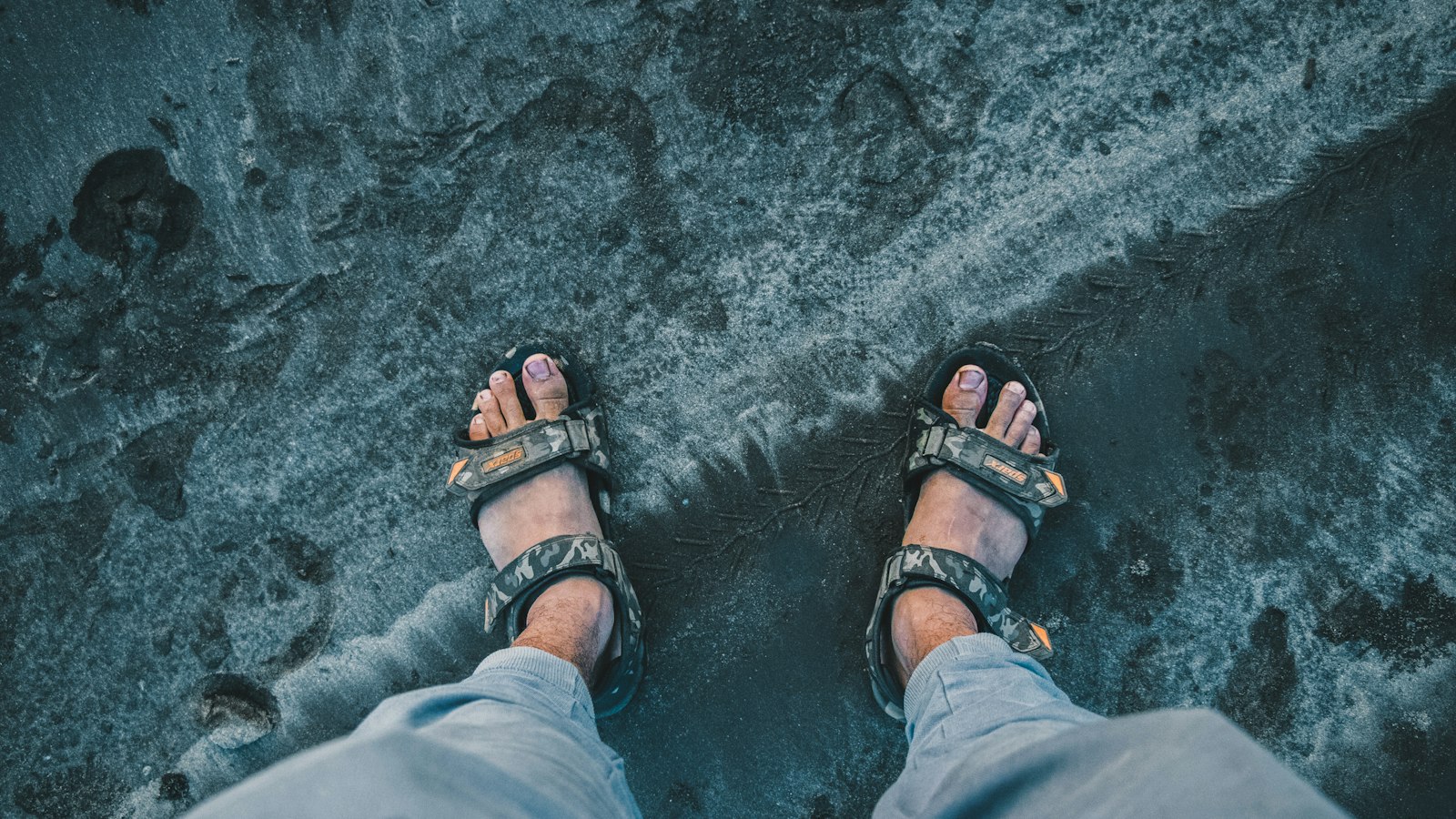 Person in grey pants wearing black strappy hiking sandals