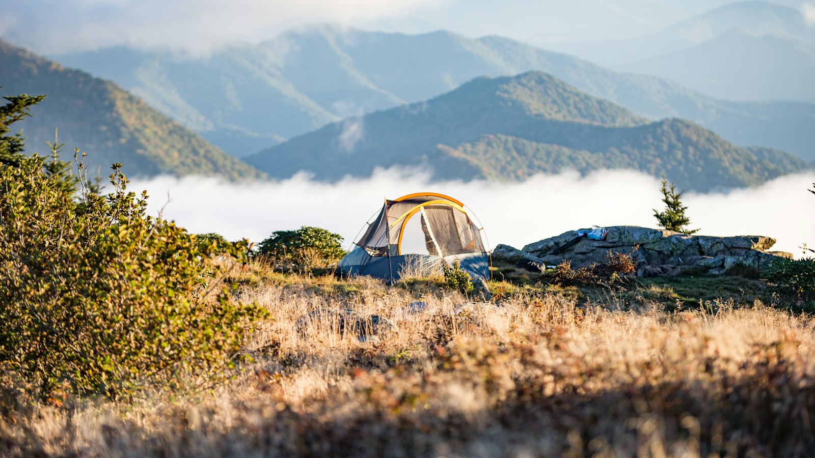 Camping tent on a mountain with fog and autumn trees