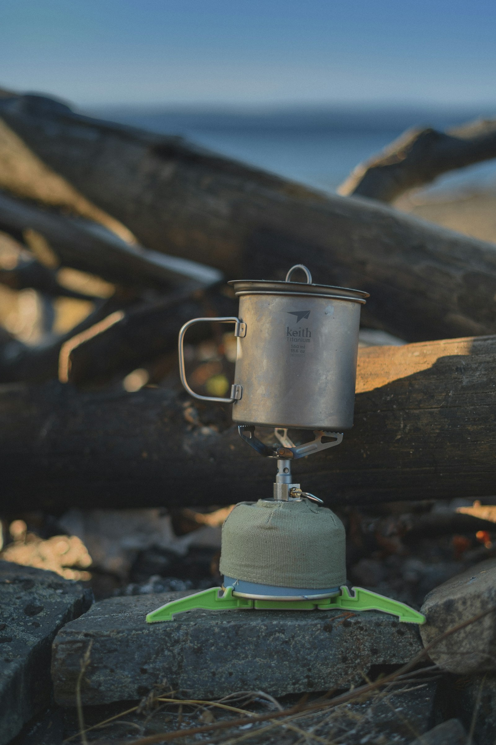 Titanium camping pot on a small portable backpacking stove outdoors