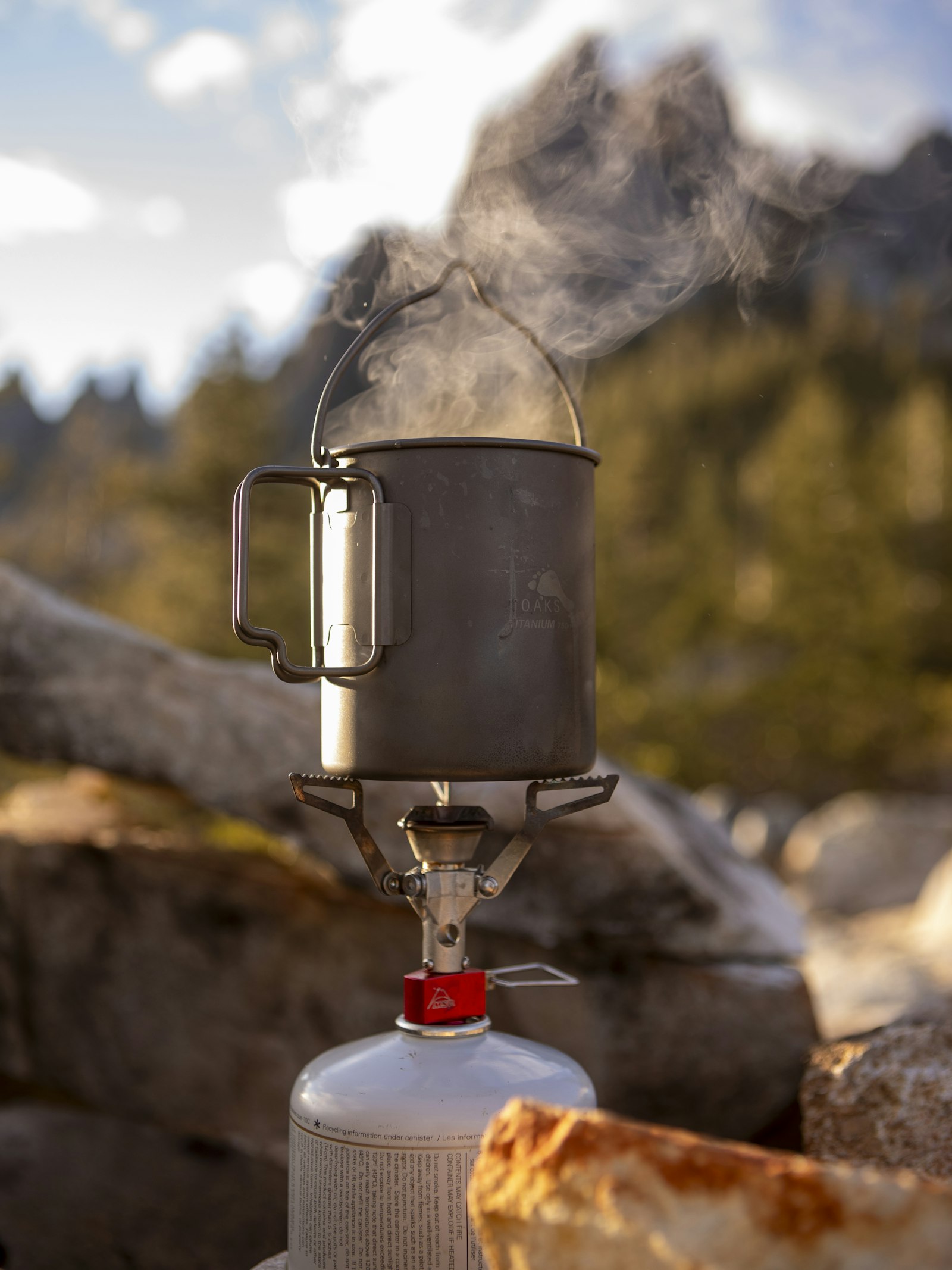 Steam rising from a camping pot on a portable backpacking stove in the mountains