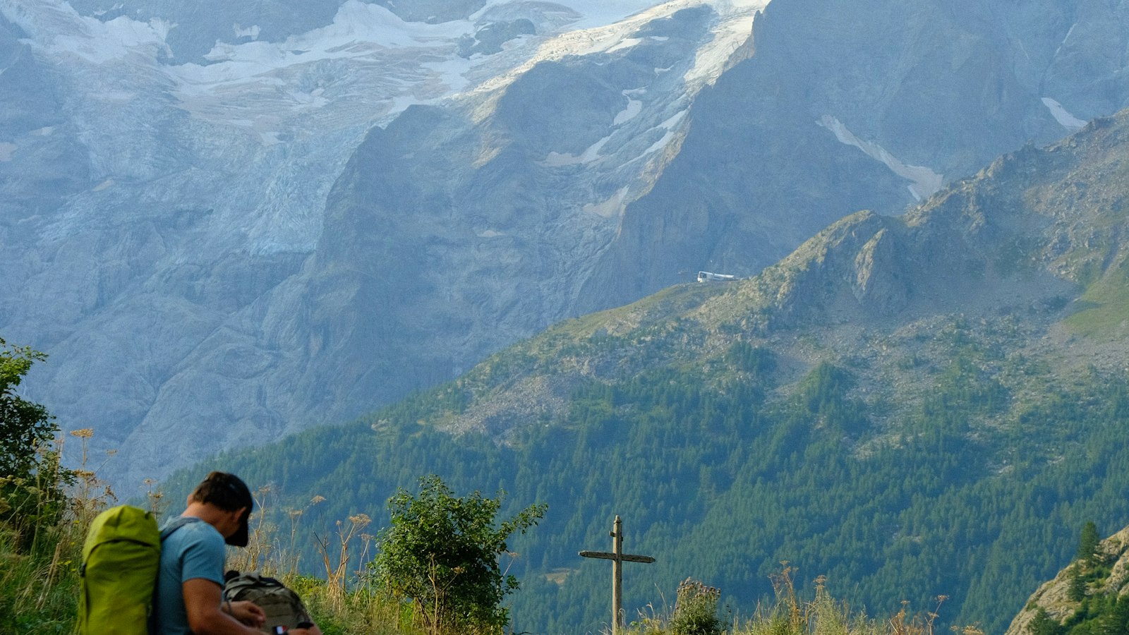 Two backpackers hiking a mountain path with a glacier in the distance