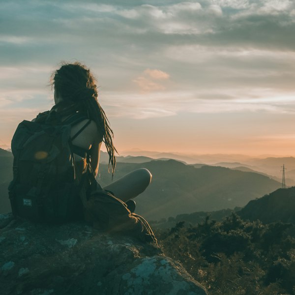 Woman resting on a rock wearing a black backpacking pack